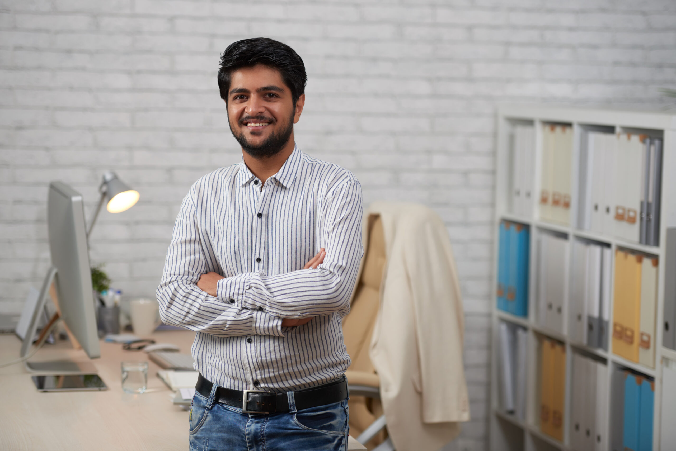 Cheerful confident Indian businessman standing with his arms crossed